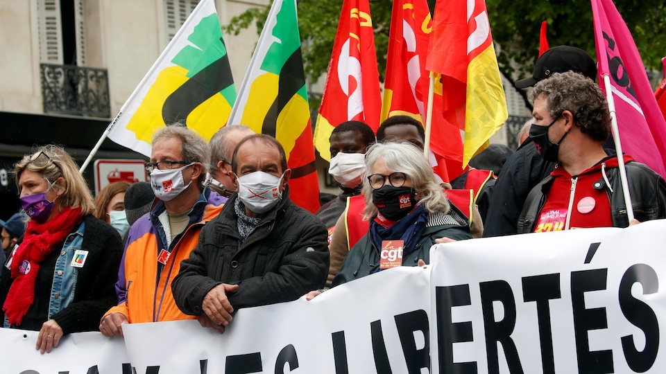 Masked protesters holding banners. 