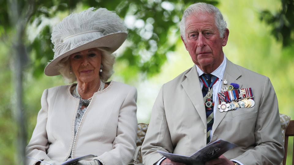 The couple is sitting together on a chair outside. 