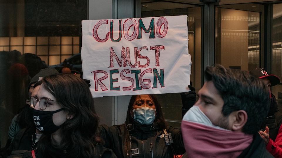 Surrounded by other protesters, a young woman holds a sign that reads 