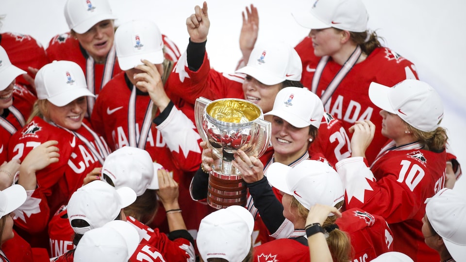 Surrounded by her teammates, she raises the trophy.