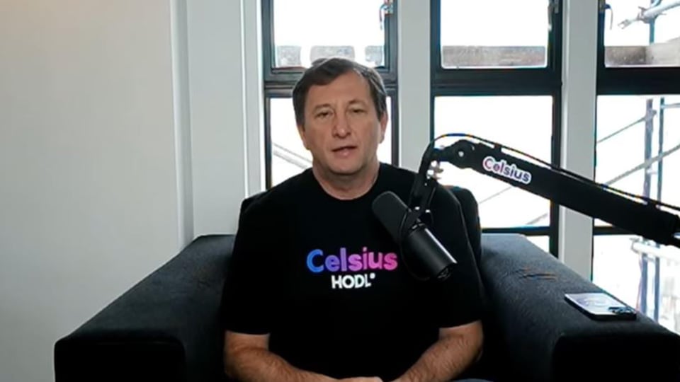 The man is sitting in front of the microphone and wearing a T-shirt with the Celsius logo and the phrase "HODL".