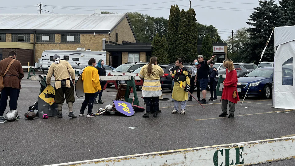 Masked people discuss in a parking lot.